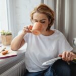 Γυναίκα που απολαμβάνει μια ήρεμη πρωινή ρουτίνα ευεξίας δίπλα στο παράθυρο.